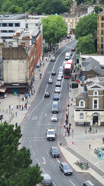 A narrow cobblestone alleyway situated between tall, multi-storey brick and stone residential buildings in an urban area. The buildings display a variety of architectural styles, with some featuring b